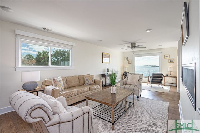 living room with a water view, hardwood / wood-style floors, and ceiling fan