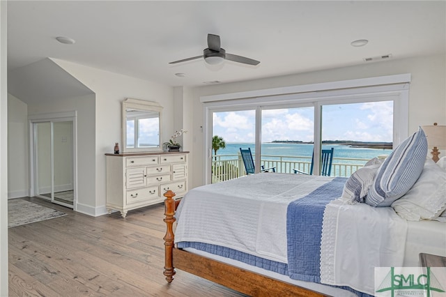 bedroom with a water view, ceiling fan, access to exterior, and light wood-type flooring