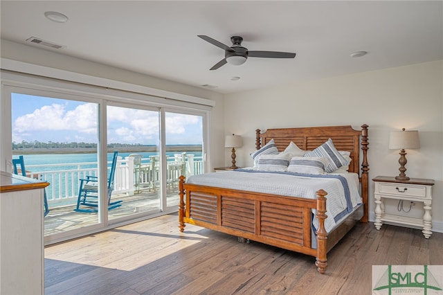 bedroom featuring a water view, ceiling fan, hardwood / wood-style floors, and access to outside