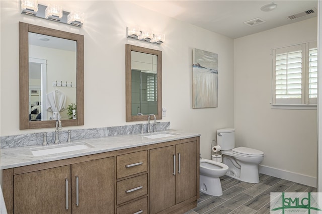 bathroom with a bidet, vanity, and toilet