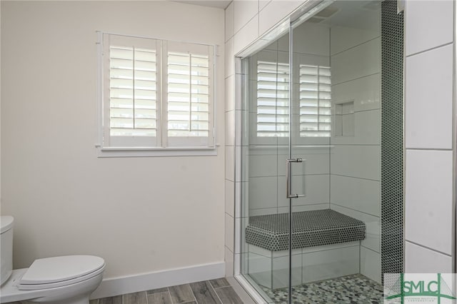 bathroom with hardwood / wood-style flooring, an enclosed shower, and toilet