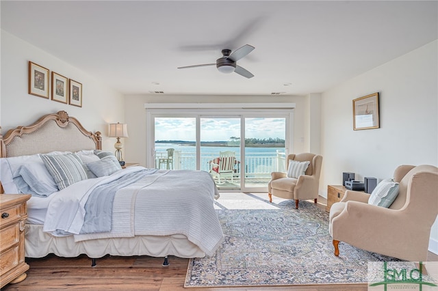 bedroom featuring hardwood / wood-style flooring, access to outside, ceiling fan, and a water view