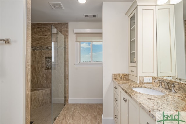 bathroom with vanity and a tile shower