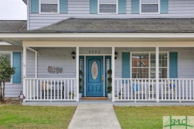 doorway to property with a porch and a lawn