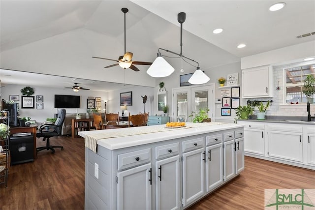 kitchen with hanging light fixtures, white cabinetry, a kitchen island, and dark wood-type flooring