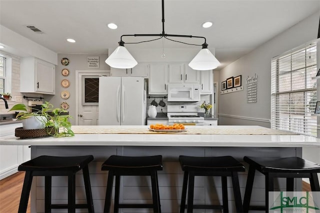 kitchen featuring white cabinetry, hanging light fixtures, white appliances, and a healthy amount of sunlight