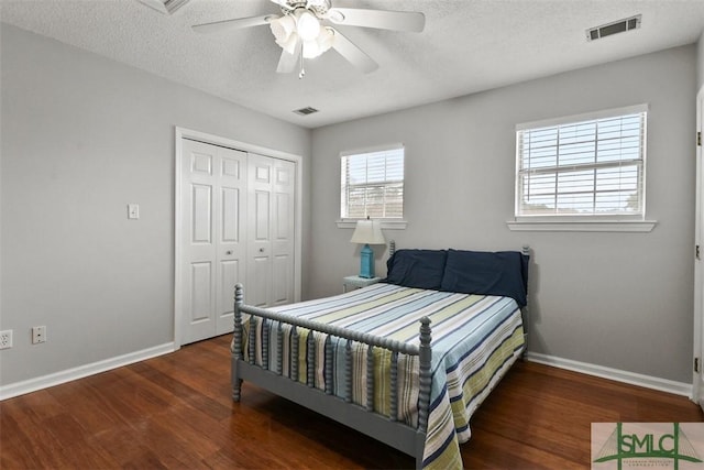 bedroom with ceiling fan, dark hardwood / wood-style floors, a closet, and a textured ceiling