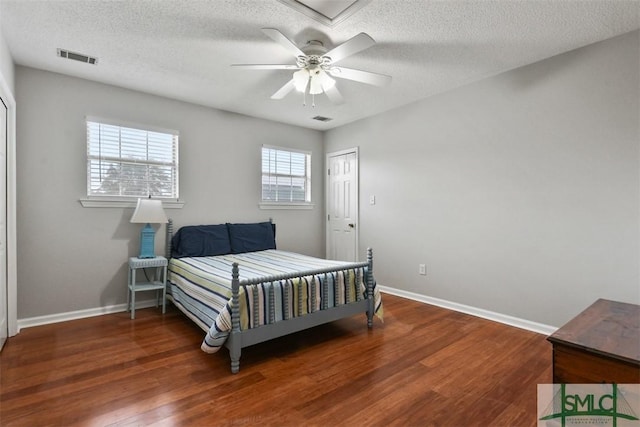 bedroom with ceiling fan, dark hardwood / wood-style floors, and a textured ceiling