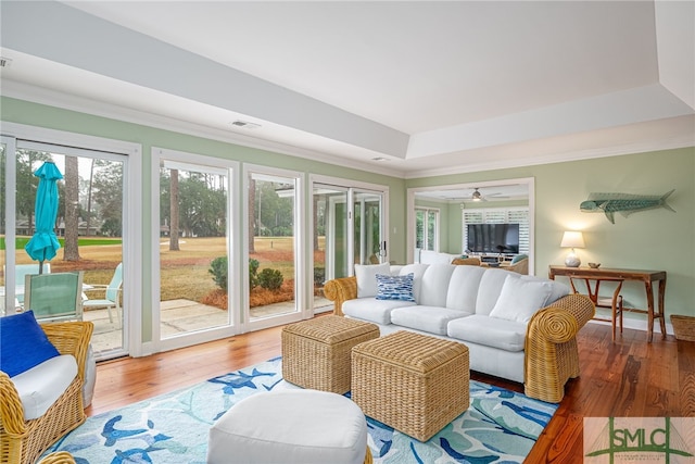 living room with ornamental molding, a tray ceiling, and hardwood / wood-style floors