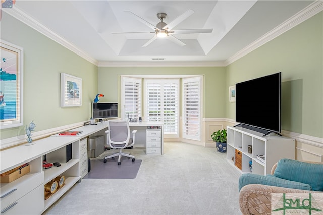 home office featuring ceiling fan, ornamental molding, a tray ceiling, and light carpet