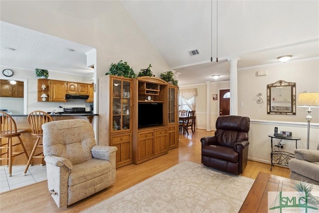 living room featuring lofted ceiling, light hardwood / wood-style flooring, ornamental molding, and ornate columns