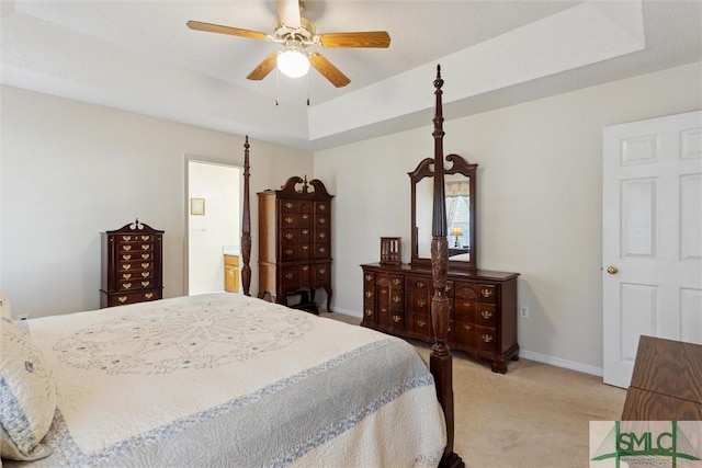 bedroom with ceiling fan, light colored carpet, and a raised ceiling