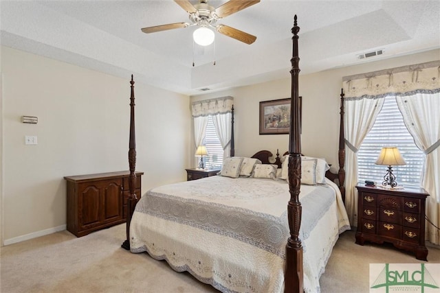 carpeted bedroom featuring a raised ceiling and ceiling fan