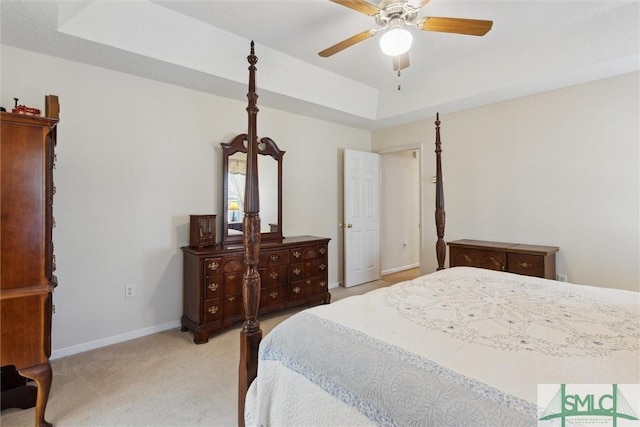 carpeted bedroom with ceiling fan and a tray ceiling