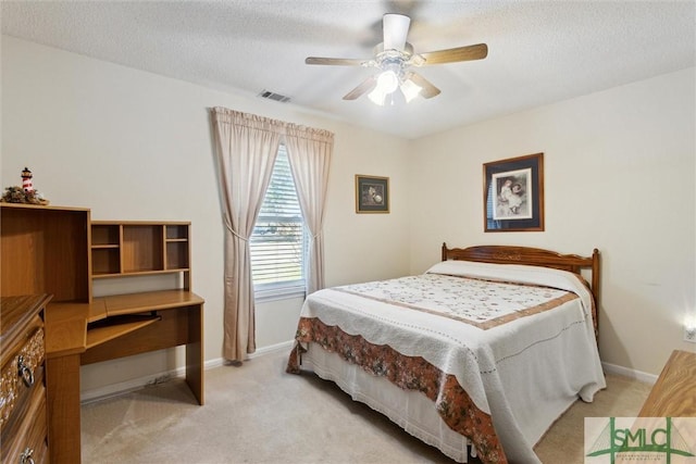 bedroom featuring ceiling fan, light carpet, and a textured ceiling