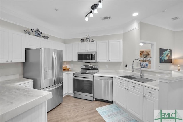 kitchen with sink, appliances with stainless steel finishes, light hardwood / wood-style floors, white cabinets, and kitchen peninsula