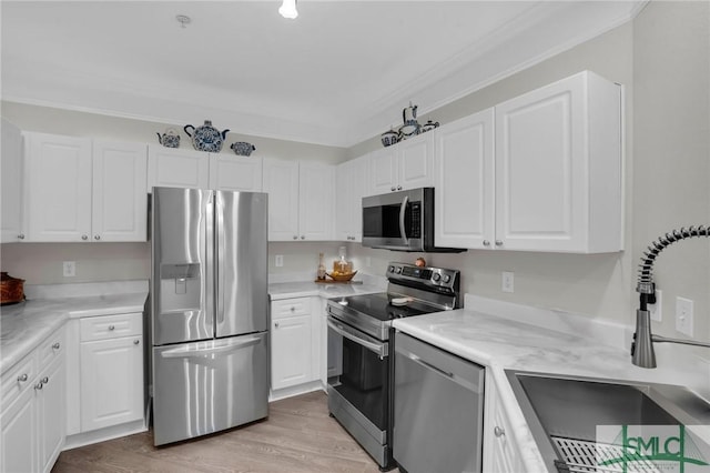 kitchen featuring sink, light hardwood / wood-style flooring, appliances with stainless steel finishes, ornamental molding, and white cabinets