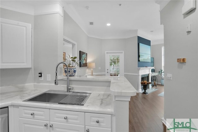 kitchen featuring sink, white cabinetry, hardwood / wood-style floors, light stone counters, and kitchen peninsula