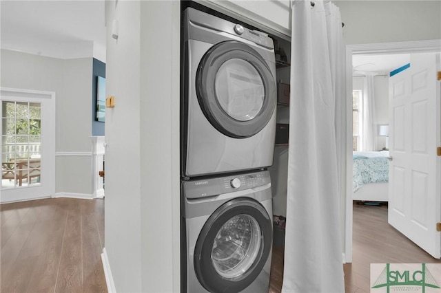 laundry room featuring hardwood / wood-style flooring and stacked washer and dryer