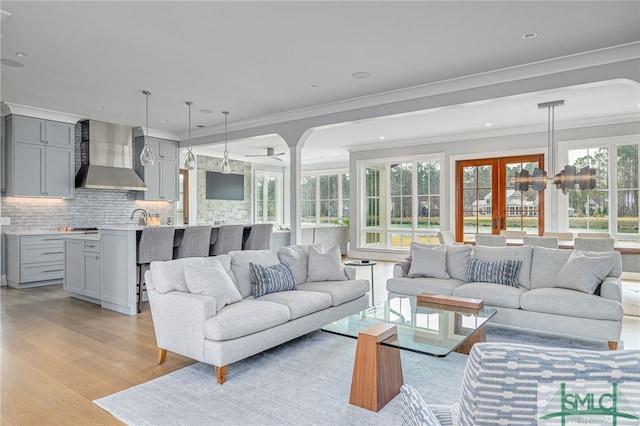 living room featuring ornamental molding, sink, light hardwood / wood-style floors, and a wealth of natural light