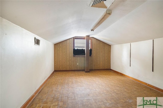 additional living space with wood walls, vaulted ceiling, and light parquet floors