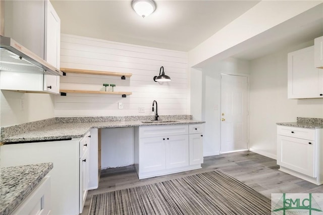 kitchen featuring sink, light stone countertops, and white cabinets