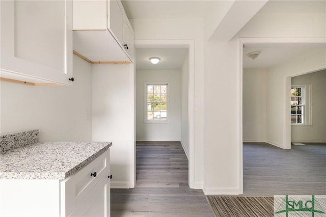 kitchen with light stone counters, light hardwood / wood-style flooring, and white cabinets