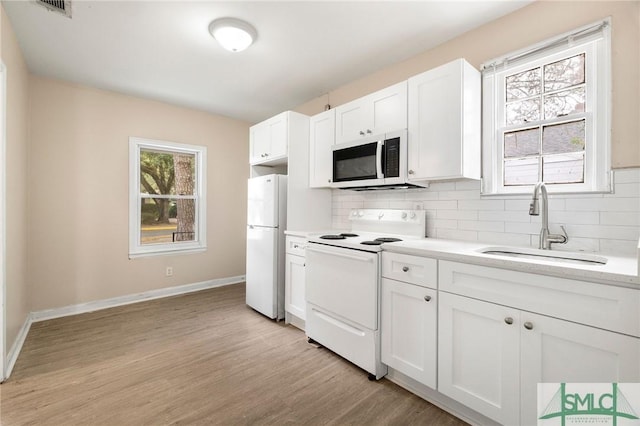 kitchen featuring sink, white cabinetry, white appliances, a healthy amount of sunlight, and decorative backsplash