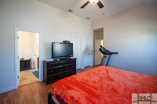 bedroom with ceiling fan, wood-type flooring, ensuite bathroom, and high vaulted ceiling