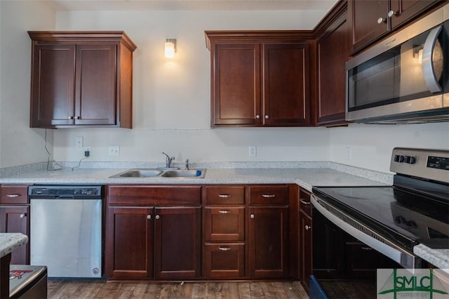 kitchen with dark wood-type flooring, stainless steel appliances, light stone countertops, and sink