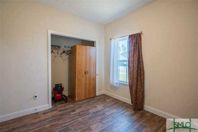 unfurnished bedroom with dark hardwood / wood-style flooring and a closet