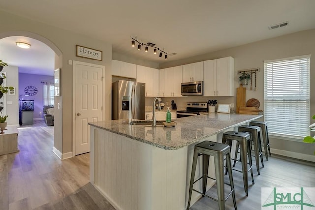 kitchen featuring a kitchen bar, sink, white cabinetry, appliances with stainless steel finishes, and kitchen peninsula