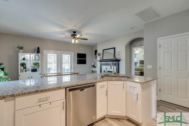 kitchen with light stone countertops, sink, stainless steel dishwasher, and white cabinets