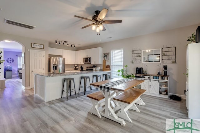 dining room featuring ceiling fan, sink, and light hardwood / wood-style flooring