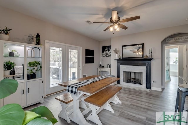 dining space featuring ceiling fan, a fireplace, and light hardwood / wood-style flooring