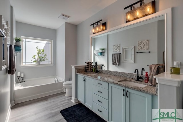 bathroom with vanity, a tub, hardwood / wood-style floors, and toilet