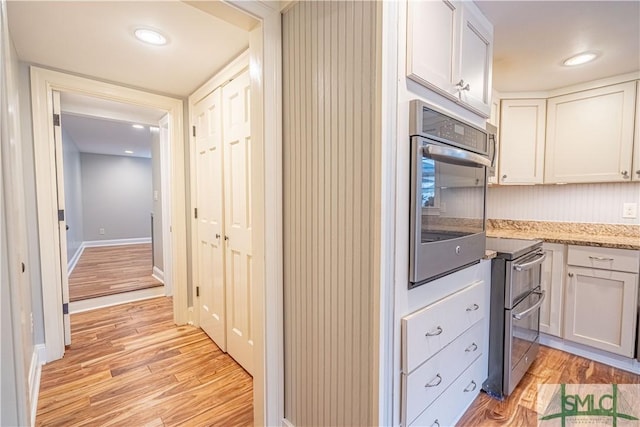 kitchen with stainless steel appliances, light wood-type flooring, and white cabinets