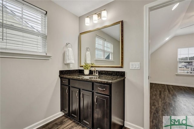 bathroom with wood-type flooring, vaulted ceiling, and vanity