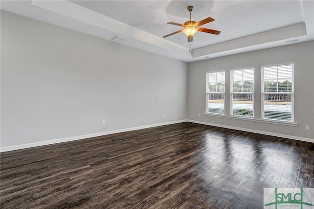 unfurnished room with dark wood-type flooring, ceiling fan, and a raised ceiling