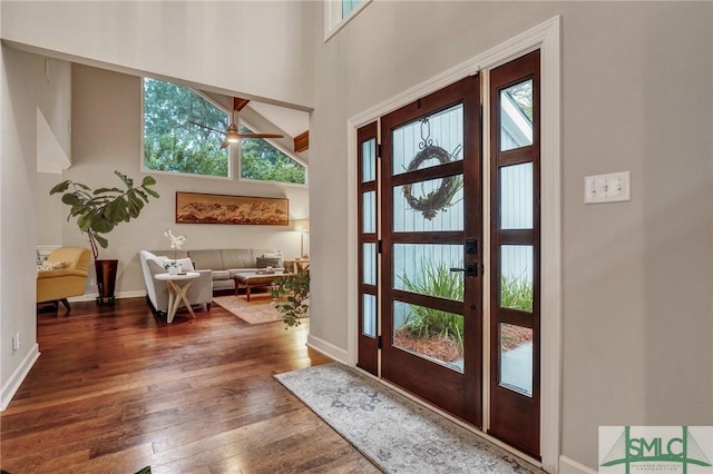 doorway with ceiling fan, dark hardwood / wood-style floors, and a high ceiling