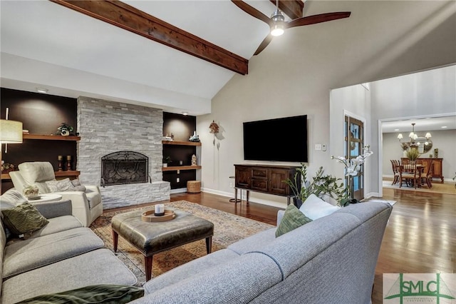 living room with hardwood / wood-style flooring, ceiling fan with notable chandelier, high vaulted ceiling, a stone fireplace, and beamed ceiling