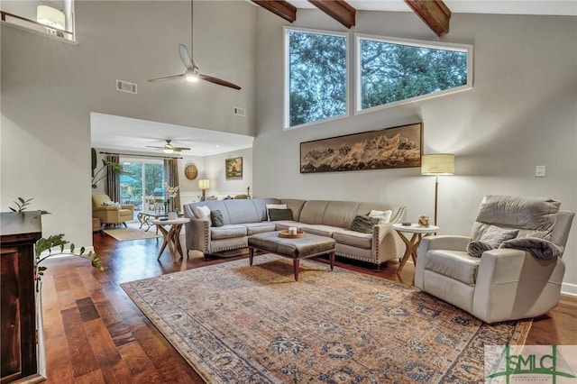 living room with dark wood-type flooring, ceiling fan, and beamed ceiling