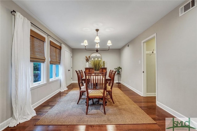 dining space featuring dark wood-type flooring and a chandelier