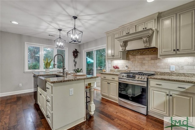 kitchen featuring decorative light fixtures, custom range hood, stainless steel appliances, light stone countertops, and a kitchen island with sink