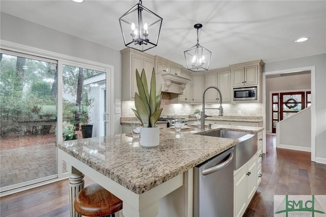 kitchen featuring decorative backsplash, hanging light fixtures, light stone counters, stainless steel appliances, and cream cabinetry