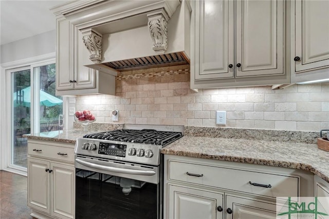 kitchen featuring decorative backsplash, light stone countertops, custom exhaust hood, and stainless steel gas range oven