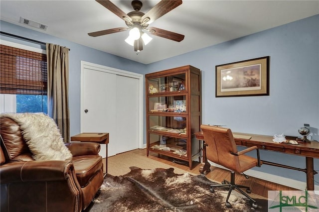 home office with light hardwood / wood-style flooring and ceiling fan