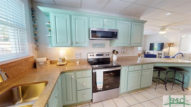 403 13th St, Tybee Island, GA 31328 - kitchen with sink, green cabinets, light tile patterned floors, ceiling fan, and stainless steel appliances