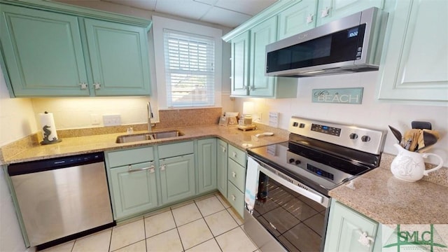 403 13th St, Tybee Island, GA 31328 - kitchen with light tile patterned flooring, sink, stainless steel appliances, light stone countertops, and a drop ceiling