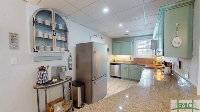 403 13th St, Tybee Island, GA 31328 - kitchen with stainless steel appliances, sink, a paneled ceiling, and light tile patterned floors